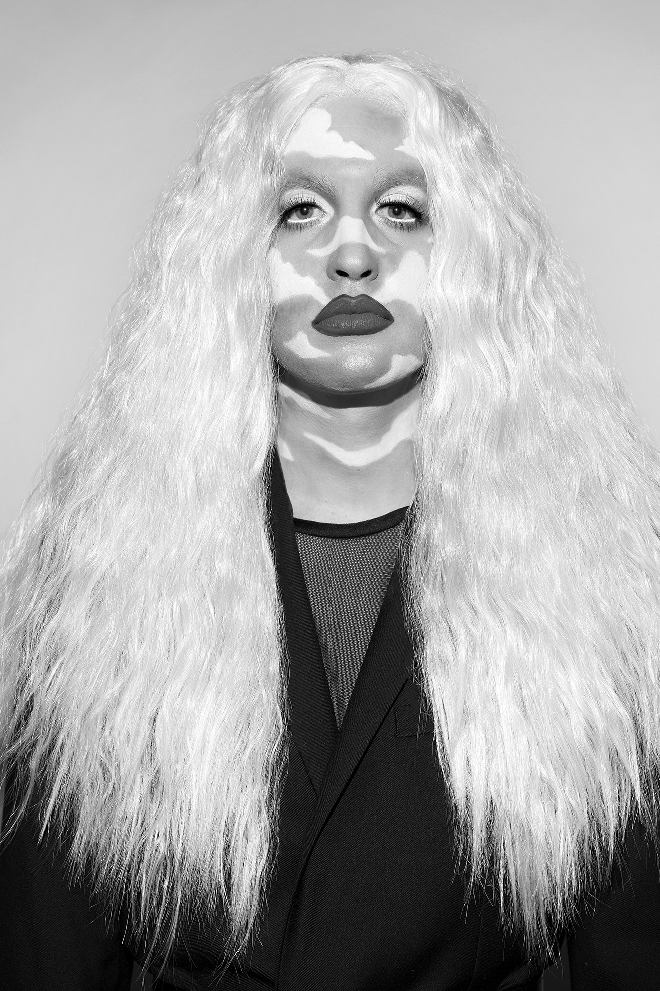 Close up of Jesse in drag with cloud facepaint on and white hair against a white background